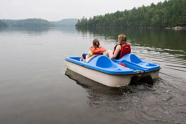 Photo of A mother and daughter riding a pedelo wearing life jackets