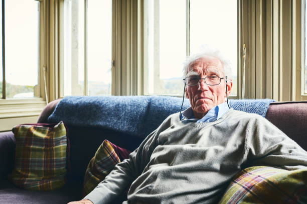 istock Senior man sitting on couch at home 941789412