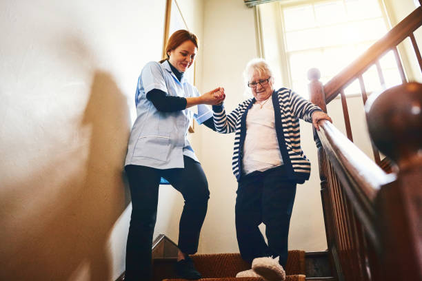 pflegeperson helfen senior frau treppen hinunter - häusliche pflege stock-fotos und bilder