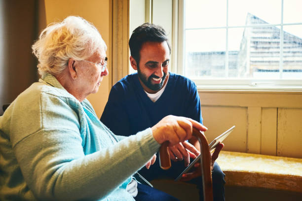 pielęgniarka płci męskiej pokazująca cyfrowy tablet starszej kobiecie - ipad senior adult 70s adult zdjęcia i obrazy z banku zdjęć