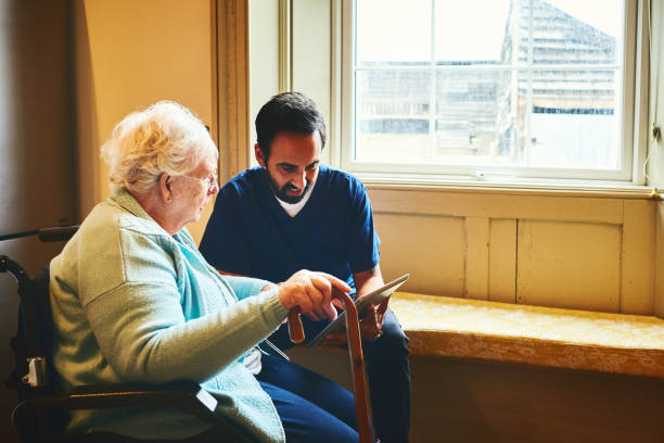 istock Home carer with elderly woman using digital tablet 941789824