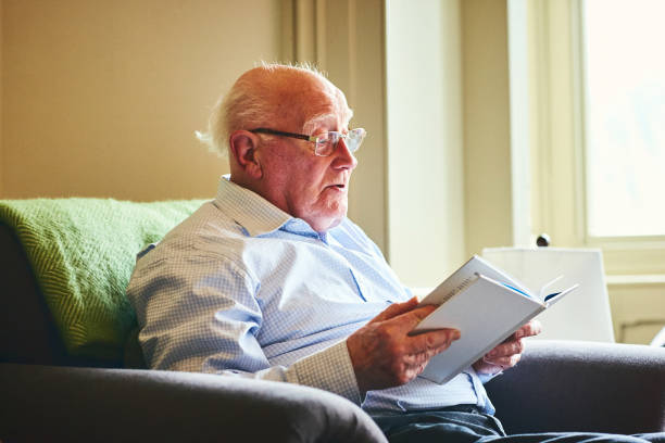 istock Senior man reading a book at home 941789826