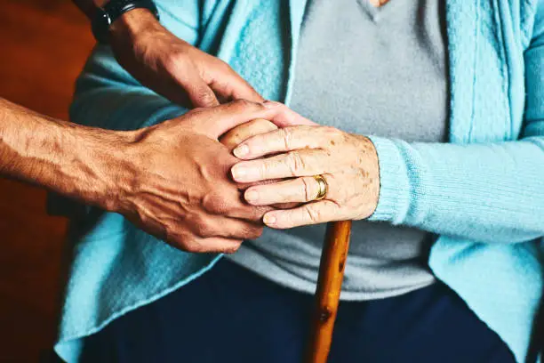 Close up of male carer holding hands of senior woman, home caregiver showing support for elderly patient.