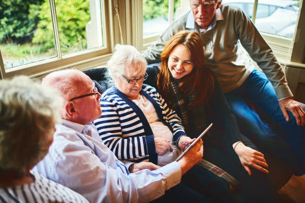 istock Group of senior people with young woman using digital tablet 941789882
