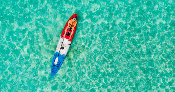 Top View on a Kayak boat on the turquoise sea water. Scenic Aerial Top View on Man with sunglasses into a colorful Kayak. Adventure lifestyle water sport summer holiday concept. Top View on a Kayak boat on the turquoise sea water. Scenic Aerial Top View on Man with sunglasses into a colorful Kayak. Adventure lifestyle water sport summer holiday concept. kayak surfing stock pictures, royalty-free photos & images