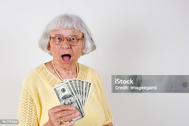 A Surprised Senior Woman Holding 100 Bills Stock Photo - Download Image Now - Senior Women, Surprise, Currency