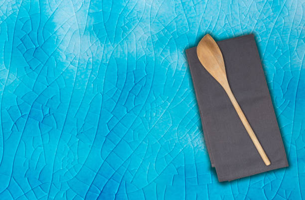 Wooden spoon and kitchen towel on turquoise krakelee.