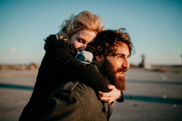 istock Cool indie couple having fun outdoors while he gives her a piggyback. 941800842