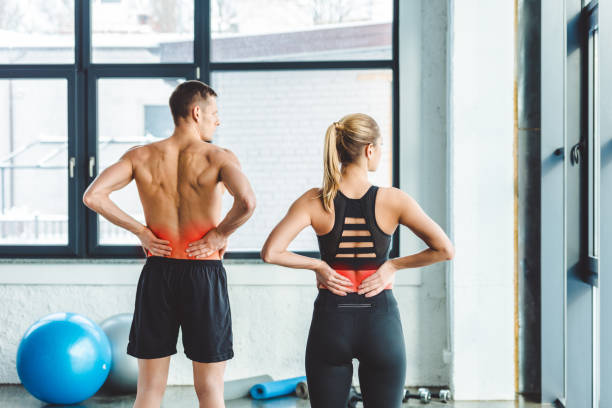 vista posterior de la pareja dolor de espalda después de hacer ejercicio en el gimnasio - back rear view pain backache fotografías e imágenes de stock