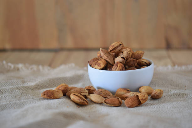 istock Almonds in white bowl on wood background. 941809088