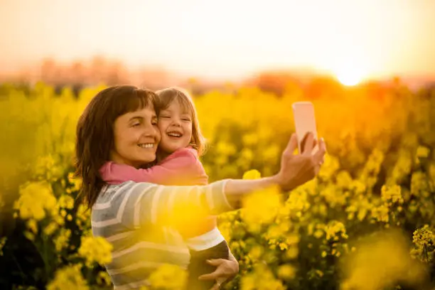 Happy mother holding girl child in arms and posing for a selfie