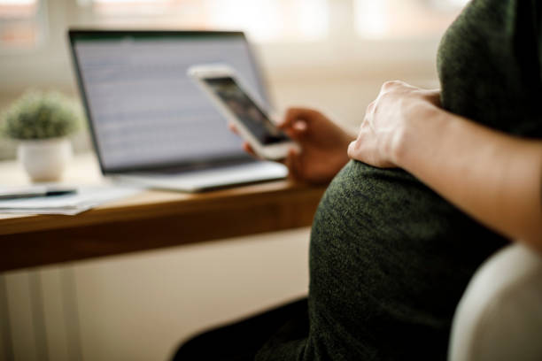 pregnant woman using mobile phone - online messaging facebook touch screen e mail imagens e fotografias de stock