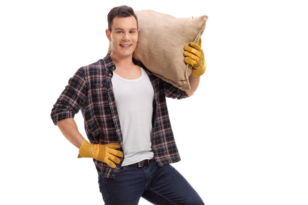istock Farmer holding a burlap sack and looking at the camera 941818396