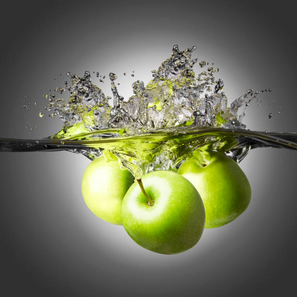 istock Three fresh green apples splashing into crystal clear water 941829856