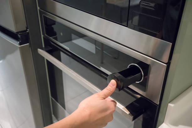 istock Hand pressing button on silver black wall oven with built-in microwave. Modern kitchen electric appliance. 941830328