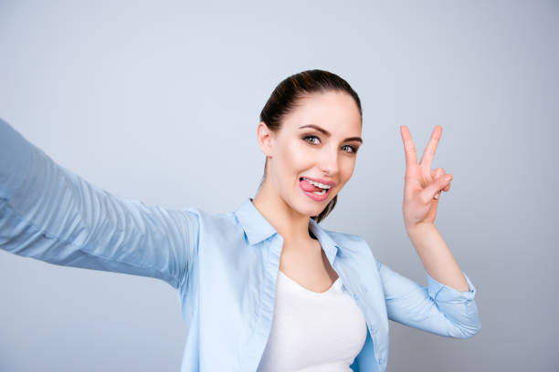 istock Comic girl gesturing v-sign and showing tongue while making selfie 941841774