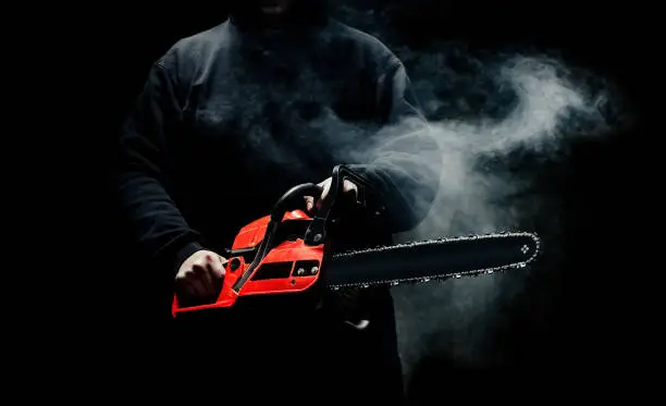 Photo of A man with a chainsaw in his hands close up
