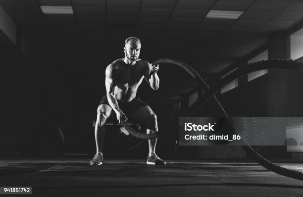 Joven Atlético Con Cuerda De Batalla Haciendo Ejercicio En El Gimnasio Foto de stock y más banco de imágenes de Entrenamiento combinado