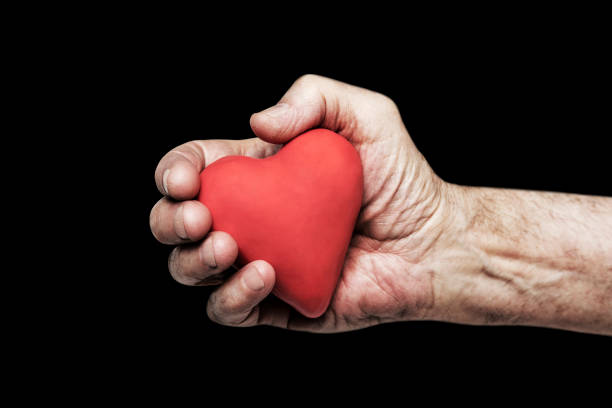 istock Red heart in senior hand over black background 941858374