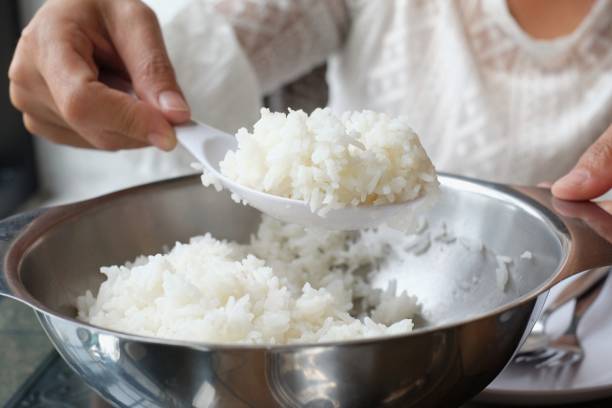istock select focus cooked rice in ladle hand held scoop from pot 941859322