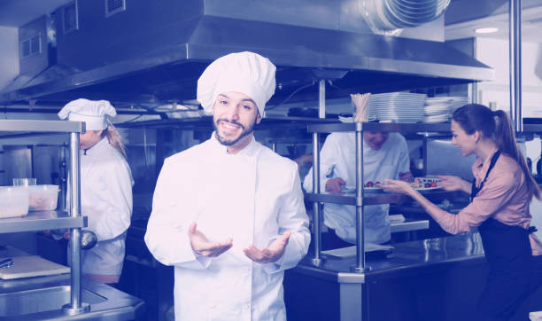 istock Chef in kitchen on background with employees 941866260