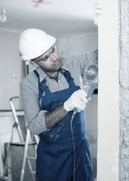 istock Male worker in helmet is sawing wall with circular saw 941872382