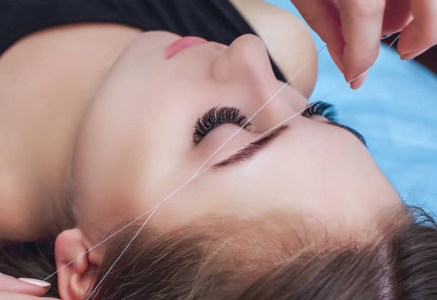 istock A make-up artist plucks an eyebrow with a thread from a beautiful brunette 941872594