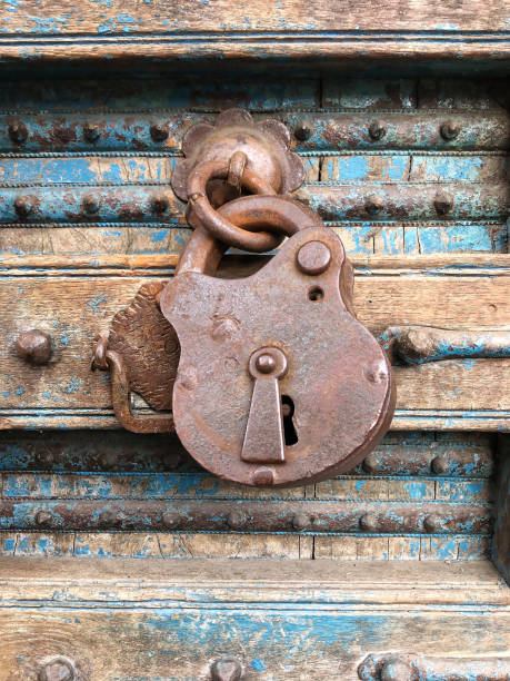 istock Old rusty padlock hanging on a dilapidated wooden door 941872684