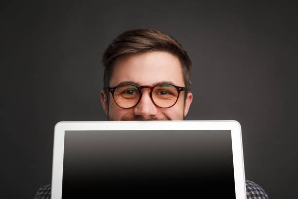 istock Cheerful man selling laptop on black 941874918