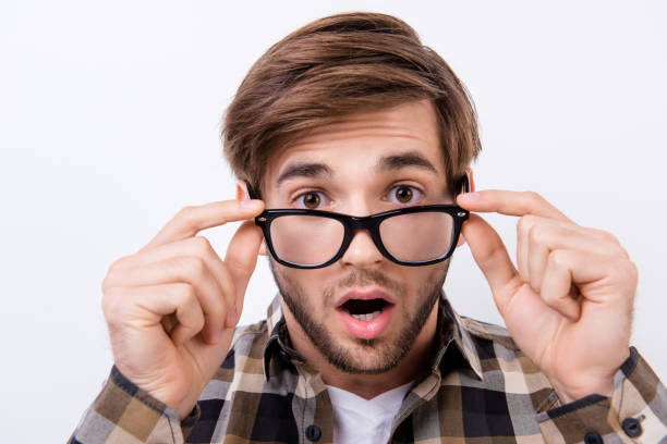 istock Surprised shocked man holding glasses and open mouth while standing on white background 941875338