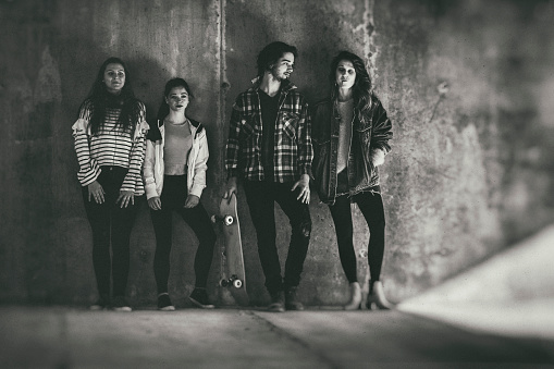 A group of teenagers hanging out against a concrete wall