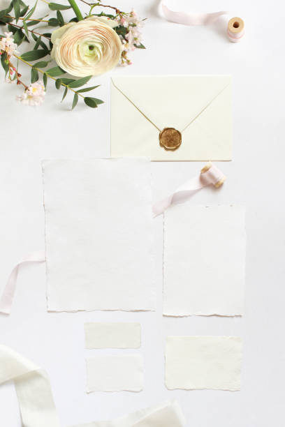 istock Feminine wedding, birthday desktop mock-ups. Blank greeting cards, envelope. Eucalyptus branches, pink cherry tree blossoms and Persian buttercup flowers. White table background. Flat lay, top view. 941878662