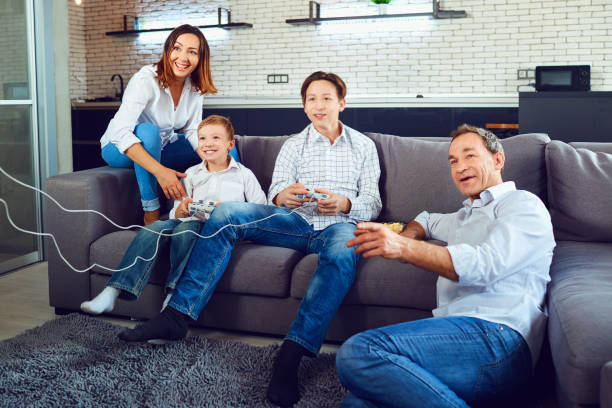 A cheerful family is playing video games while sitting on a sofa