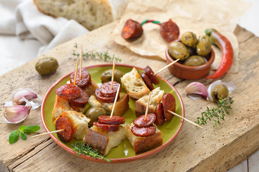 Spanish pinchos: Fried spicy chorizo sausage on roasted bread served with green olives