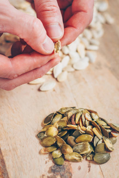 istock Close-up of a man's hand extract a pumpkin seed from a shell 941890236
