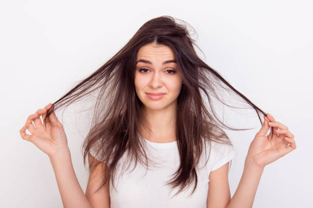 istock Sad girl showing  her damaged hair while standing white background 941890382