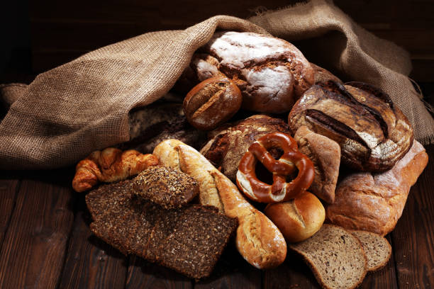istock Different kinds of bread and bread rolls on board from above. Kitchen or bakery poster design 941893966