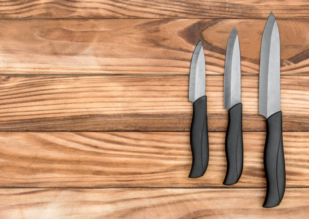 istock Three kitchen knives on wooden table. Top view. Copy space. 941893980