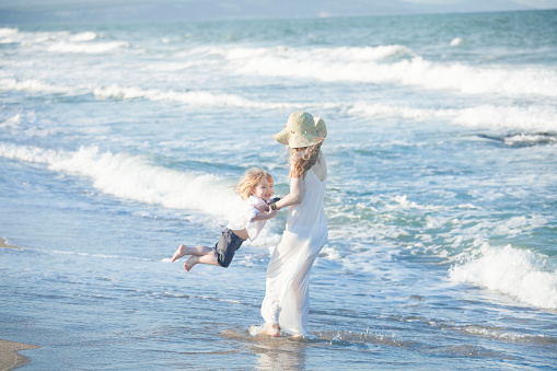 Young mother and her little child having fun on the beach