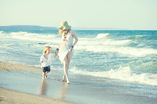 Young mother and her little child walking on the beach