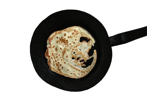 Isolated top view of a flawed crepe on a skillet with white background