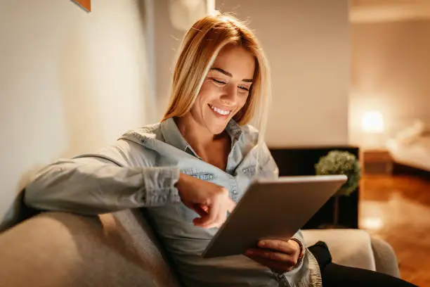 Attractive young woman holding a tablet at home