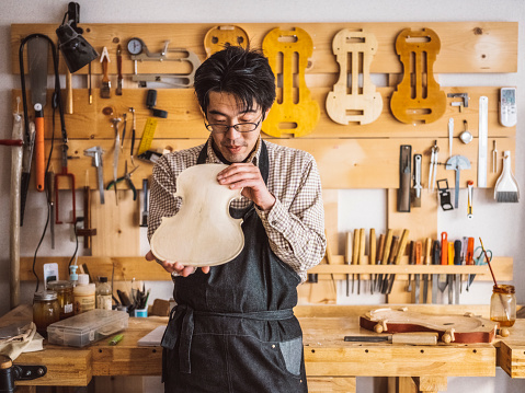 A custom violin maker works on an instrument in his shop in Tokyo, Japan.