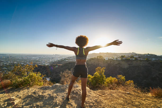 athletic african american woman celebrating reaching top of runyon canyon with arms open athletic african american woman celebrating reaching top of runyon canyon with arms open shot with lens flare canyon stock pictures, royalty-free photos & images
