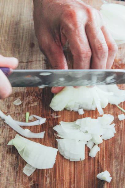 istock Cutting and chopping onion on wooden board with knife 941934546