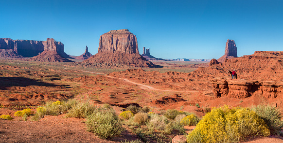 Classic panoramic view of scenic Monument Valley with horse rider at famous John Ford's Point  in beautiful golden evening light at sunset in summer, Arizona, USA