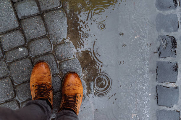 istock mans legs next to puddle. rainy weather. 941943192