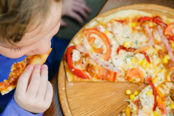 istock Child, boy, eating pizza at a restaurant, , summertime 941943710