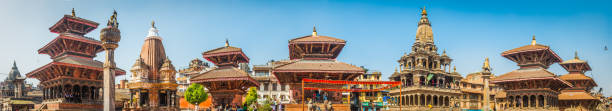 Kathmandu ancient temples and shrines Patan Durbar Square panorama Nepal Clear blue panoramic skies over the wooden temples and shrines as local tourists climb through the historic monuments of Patan Durbar Square, a UNESCO World Heritage Site in the heart of Kathmandu, Nepal's vibrant capital city. patan durbar square stock pictures, royalty-free photos & images
