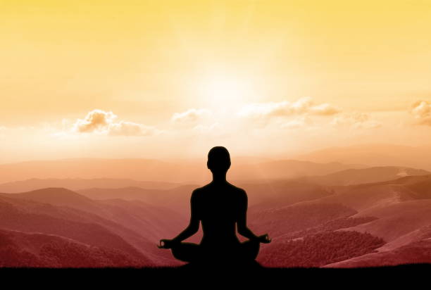 istock Yoga silhouette on the mountain in sunrays 941950628